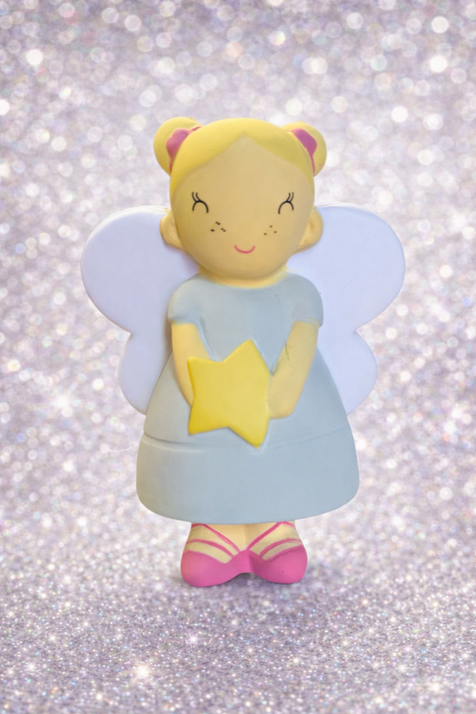 A fairy figurine with blonde hair, doll-like face, pink shoes, and large white wings, holding a yellow star, against a glittery background.