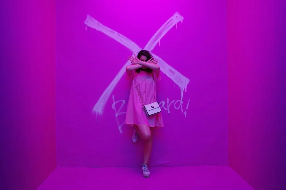 Woman in pink dress with crossed tape barriers representing setting boundaries in relationships and stopping people pleasing behaviors