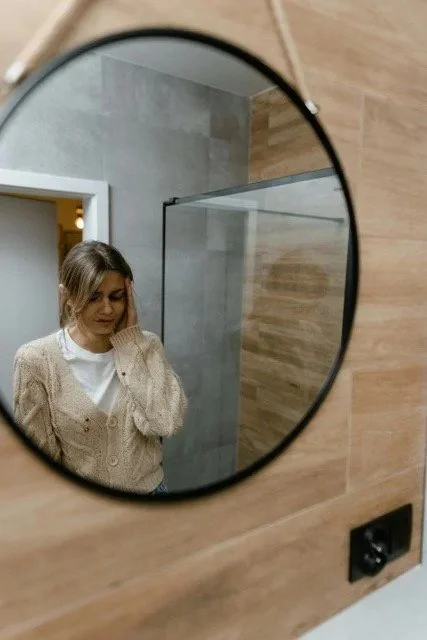 Woman seen in mirror reflection contemplating therapy after discovering infidelity
