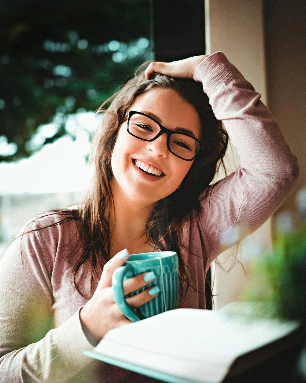 Smiling woman therapist with glasses holding coffee mug, representing success and happiness after working with a business coach.
