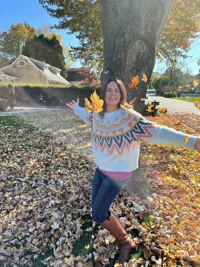 Alyse Freda-Colon, therapist business coach, throwing autumn leaves in joyful celebration