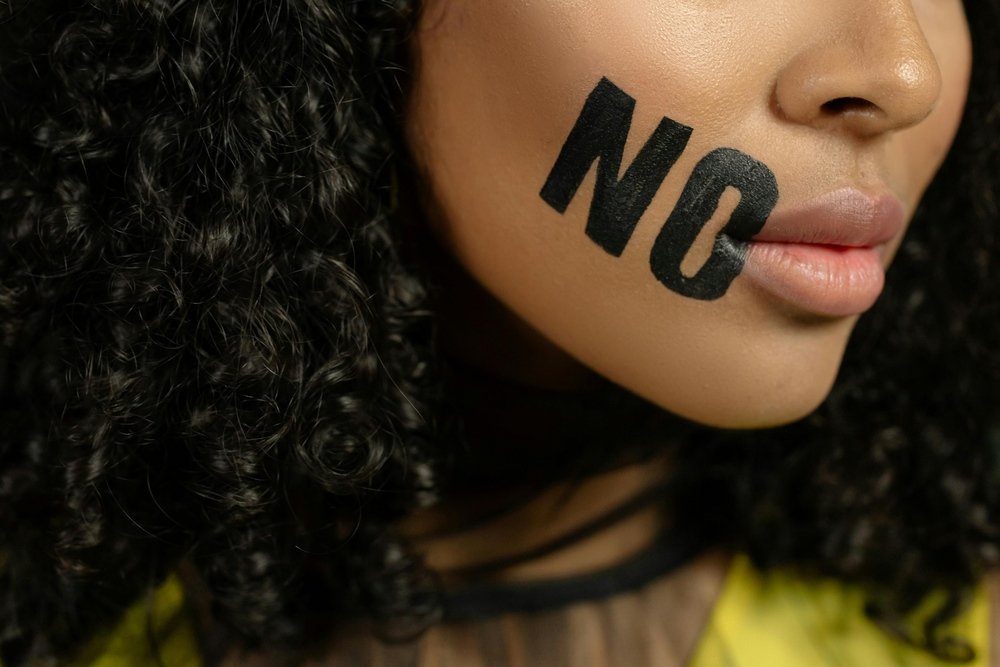 Woman with "NO" written on cheek representing learning how to say no and set boundaries in relationships