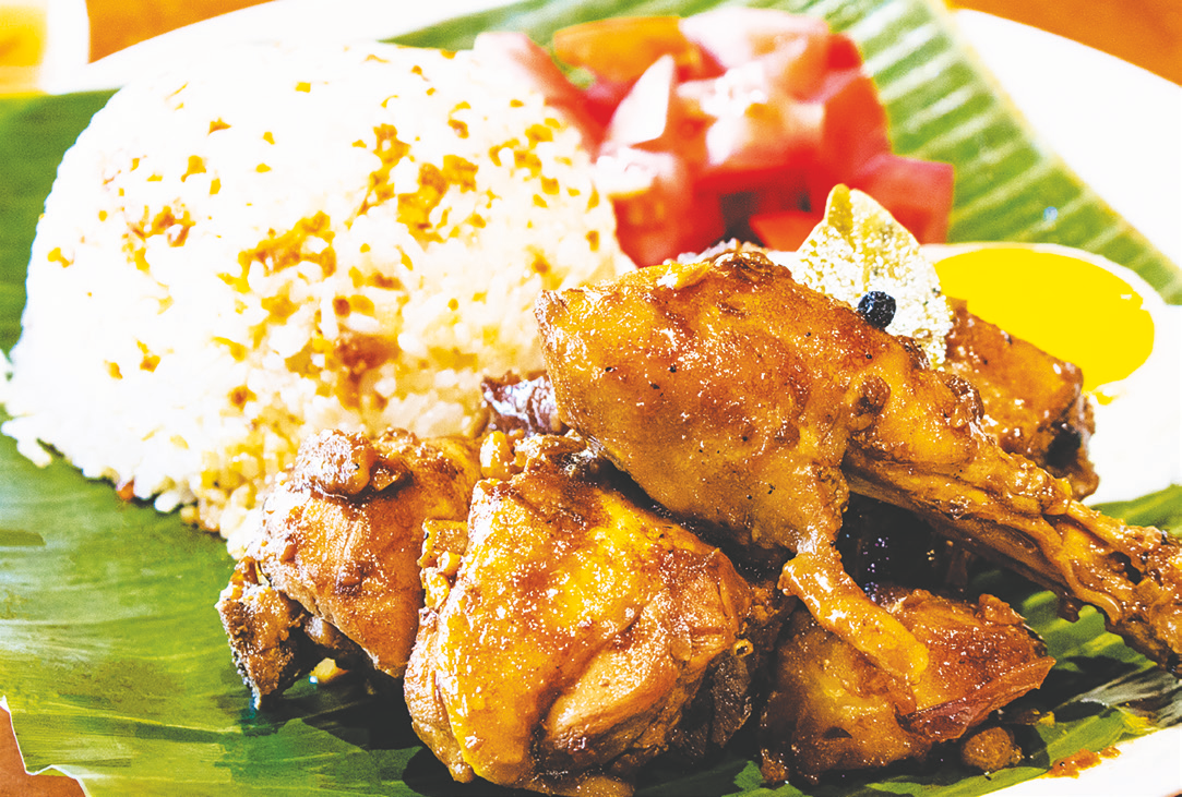 Chicken simmered in adobo sauce with vinegar, bay leaf, peppercorn, and potatoes, served with rice, fried egg, and tomato