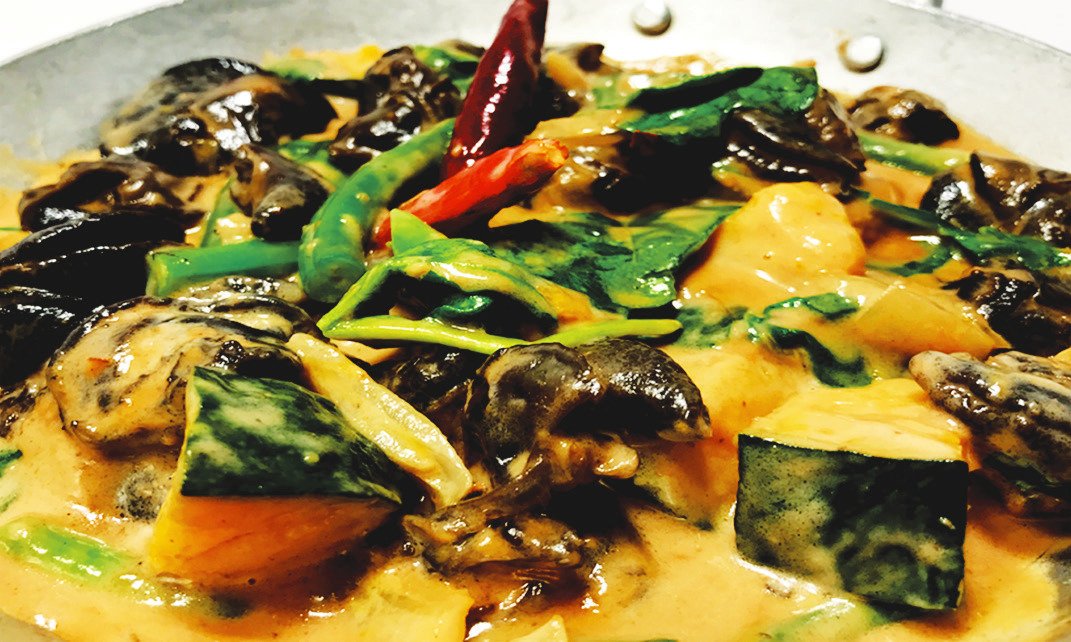 Shell-off snails in coconut sauce with green beans, squash, and chili peppers served in a plate