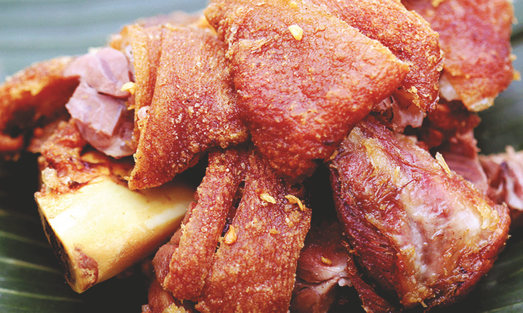 Deep‑fried pork leg served with spiced vinegar or lechon sauce
