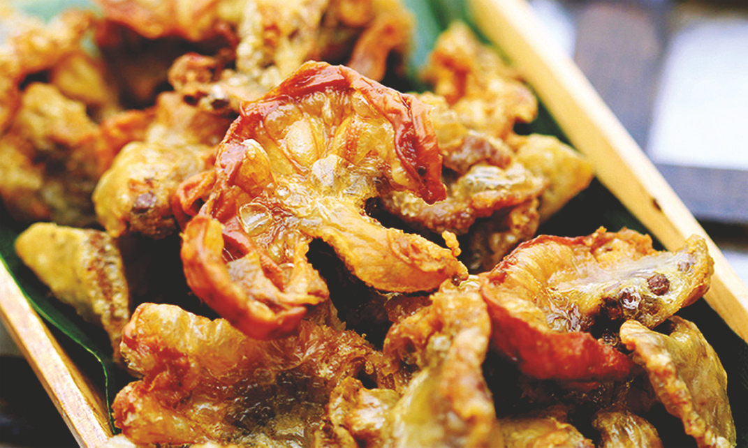Crispy pork ruffles fat piled on a wooden plate.