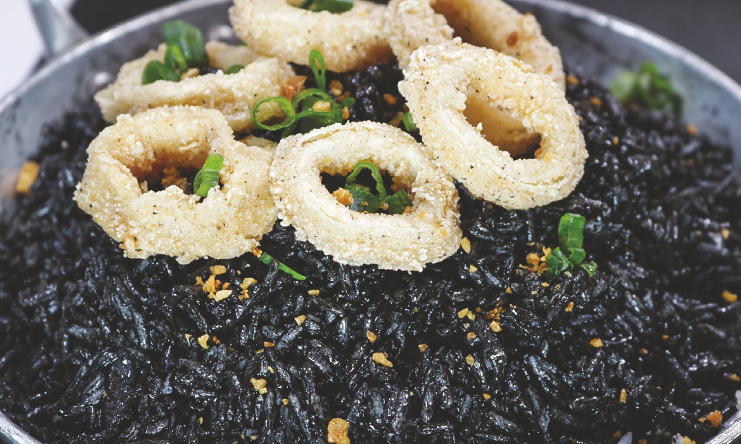 Squid ink rice topped with fried calamari rings.