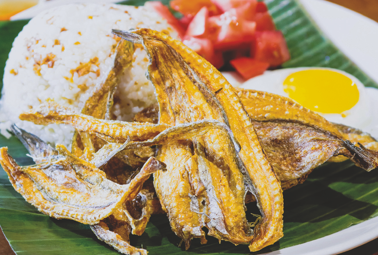 Deep fried small crispy fish served with rice, fried egg, and tomato