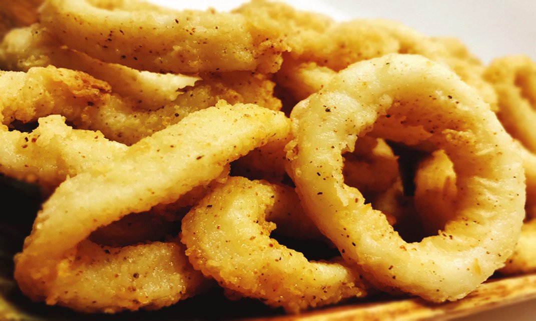 Golden brown rings of deep-fried calamari stacked on a plate.