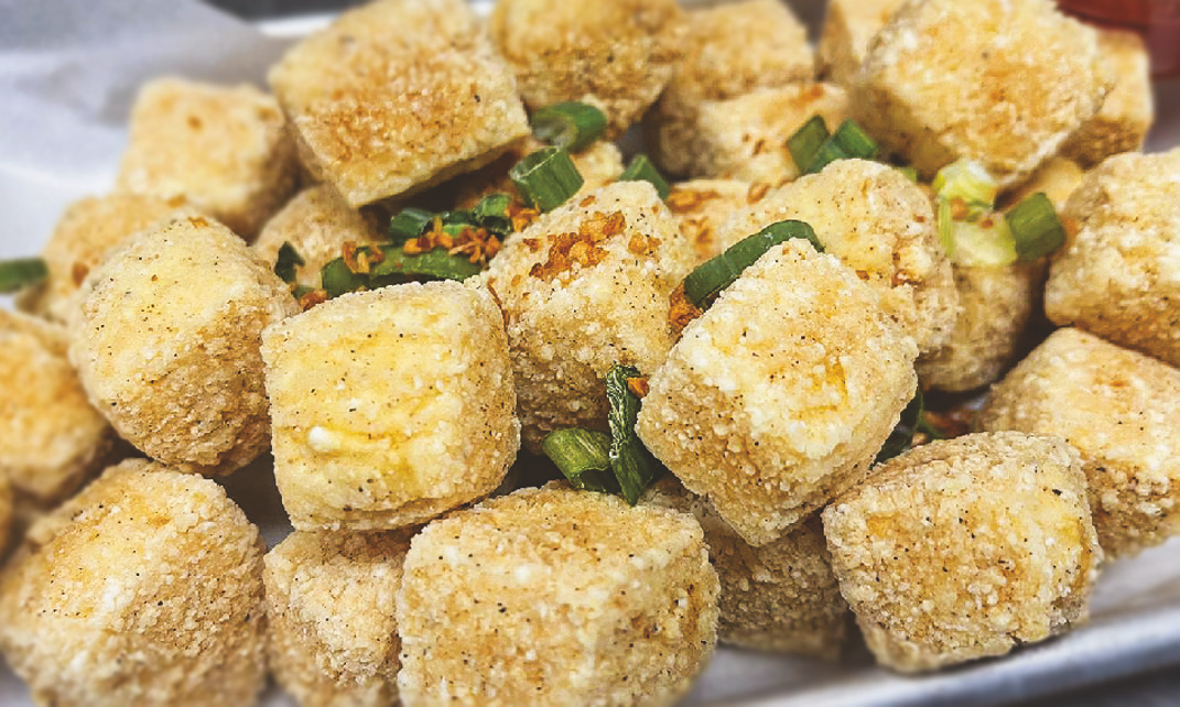 Cubes of deep-fried tofu coated in breading and garnished with green onions.