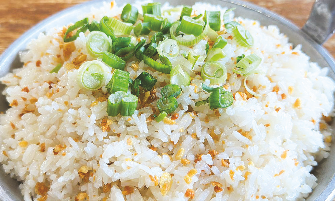Garlic rice garnished with chopped green onions and fried garlic bits.