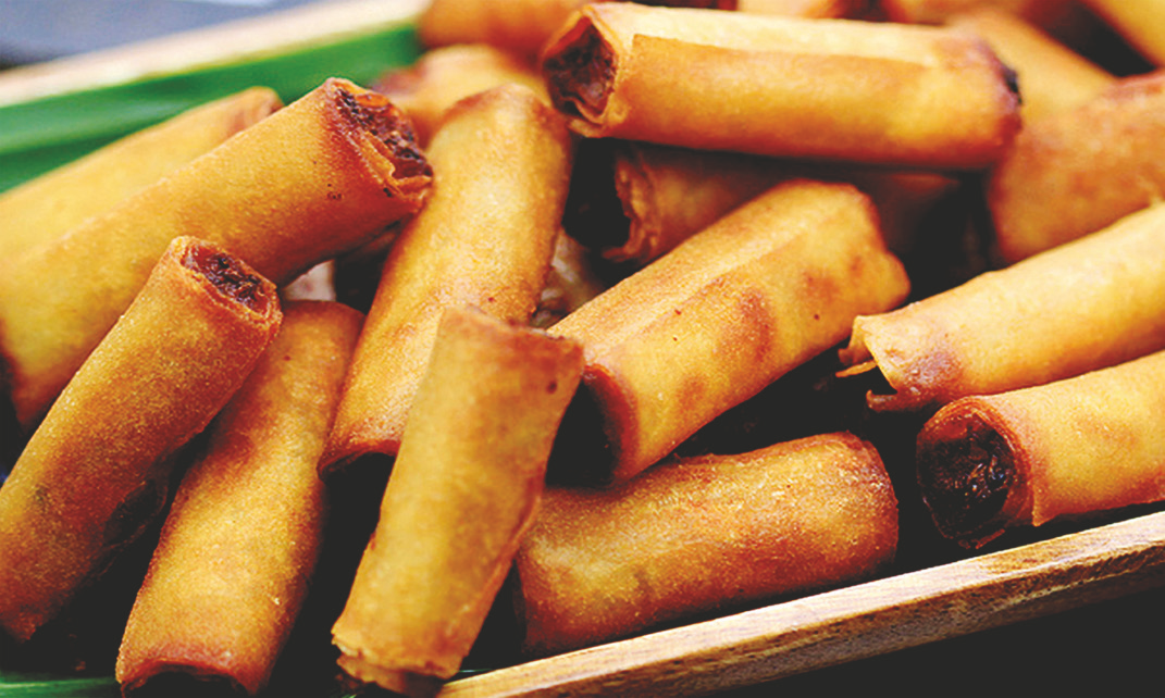 Fried spring rolls filled with chicken and vegetables arranged on a wooden tray.