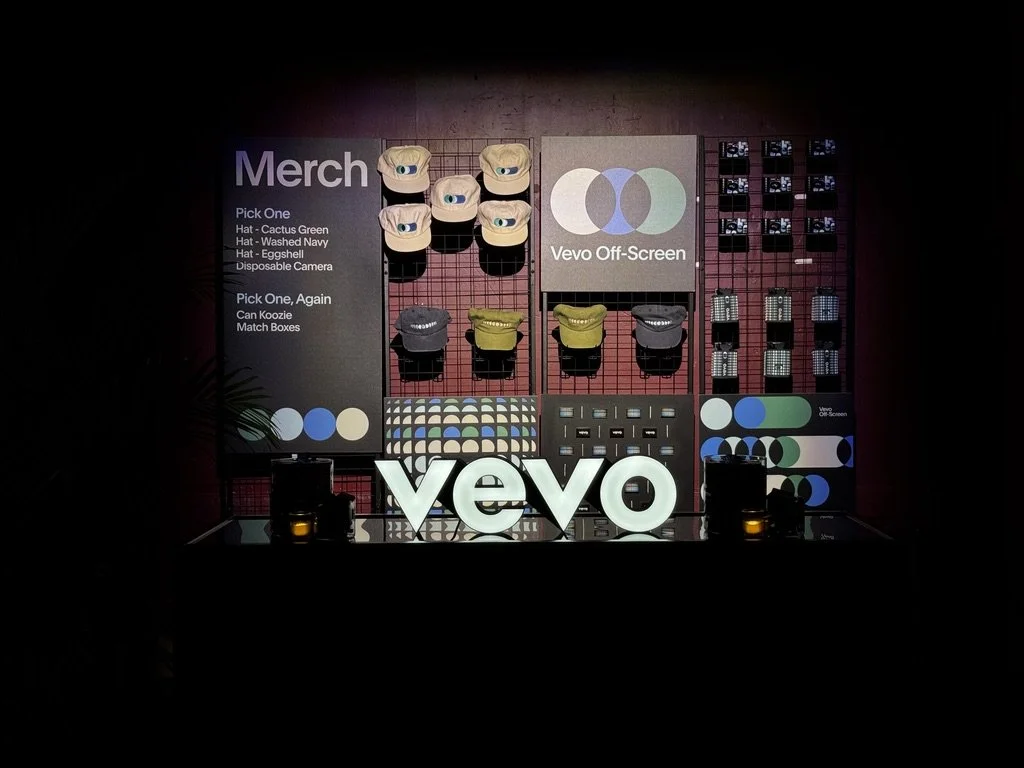 Bespoke giveaways cleanly displayed on industrial metal racks with Vevo lightbox on the forefront.