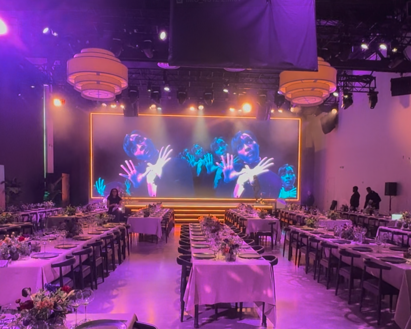 View of presentation room with custom stage and lighting set along the stage perimeter and step edge. Additionally a lighting bezel was added along the border of the LED screen evoking a "living room" feel to the space.
