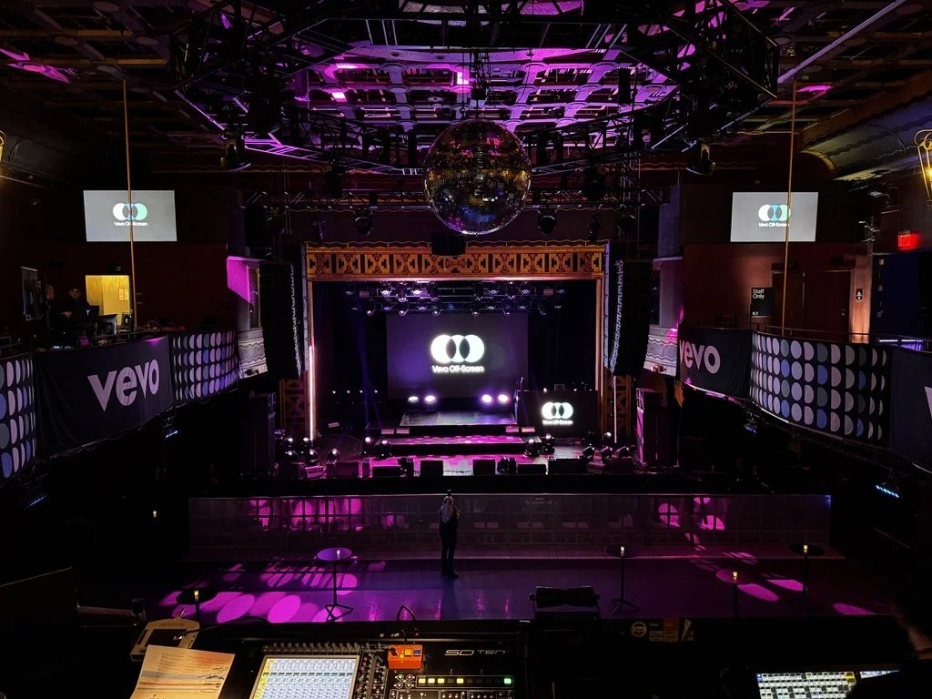 Wide view of presentation room with stage fully set including 16' x 10' LED screen, 2' x 8' LED DJ table, and 16' x 8' steel deck stage with skirting.