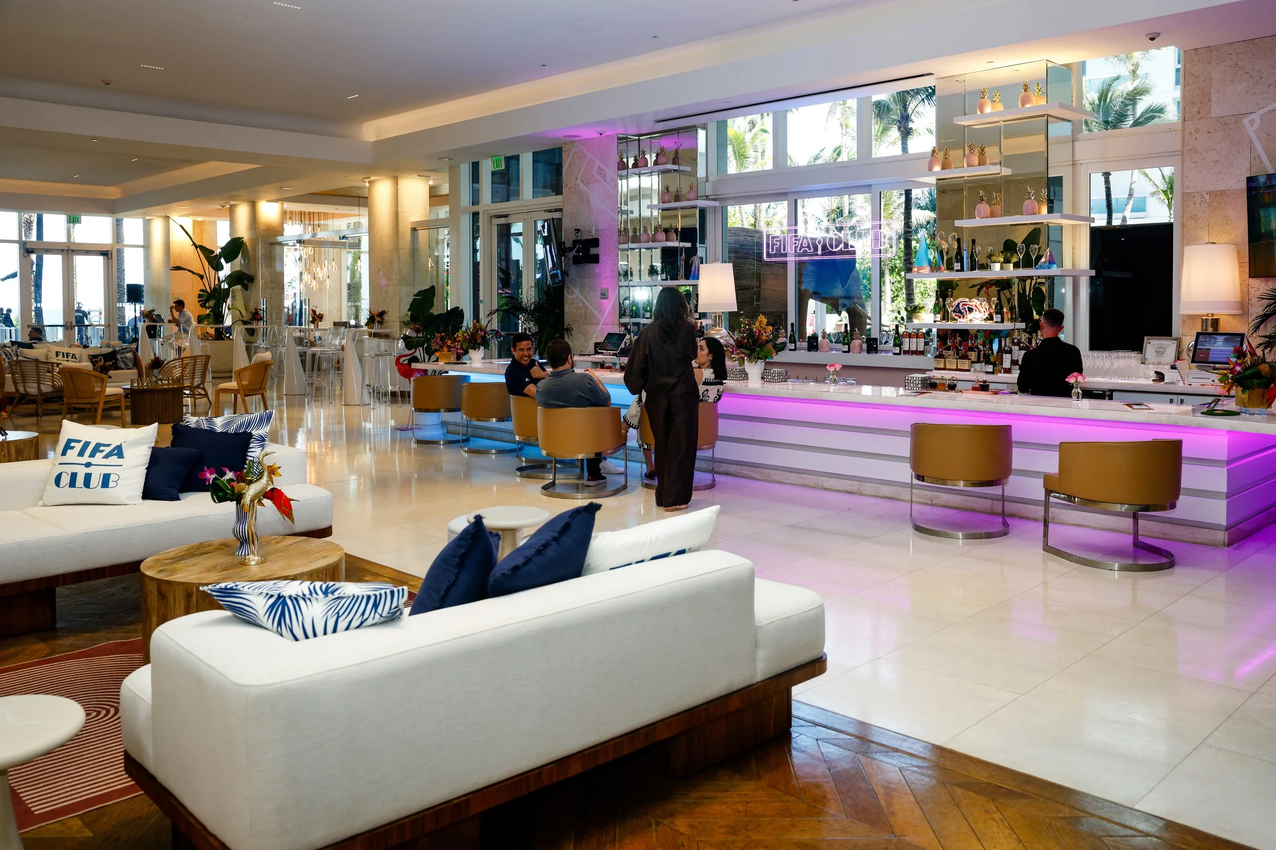Main bar takeover with perimeter lighting added on the top and bottom. Neon sign suspended in the middle of bar, and branded pillows throughout for added touch points. (Grand Beach Hotel; Miami, FL)