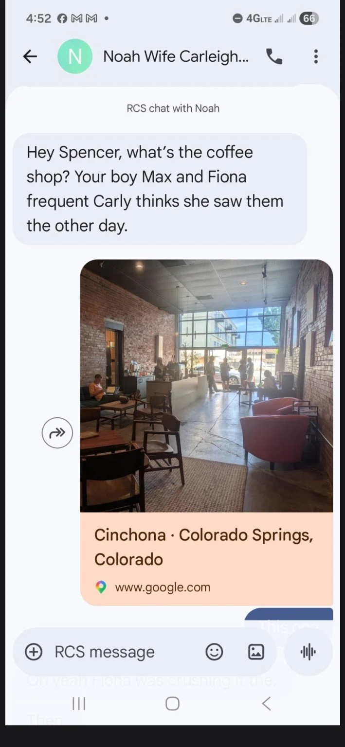 Photo of the interior of a coffee shop in Cinchona, Colorado Springs, Colorado, with several customers sitting and standing near the counter, large windows letting in natural light, and brick walls.