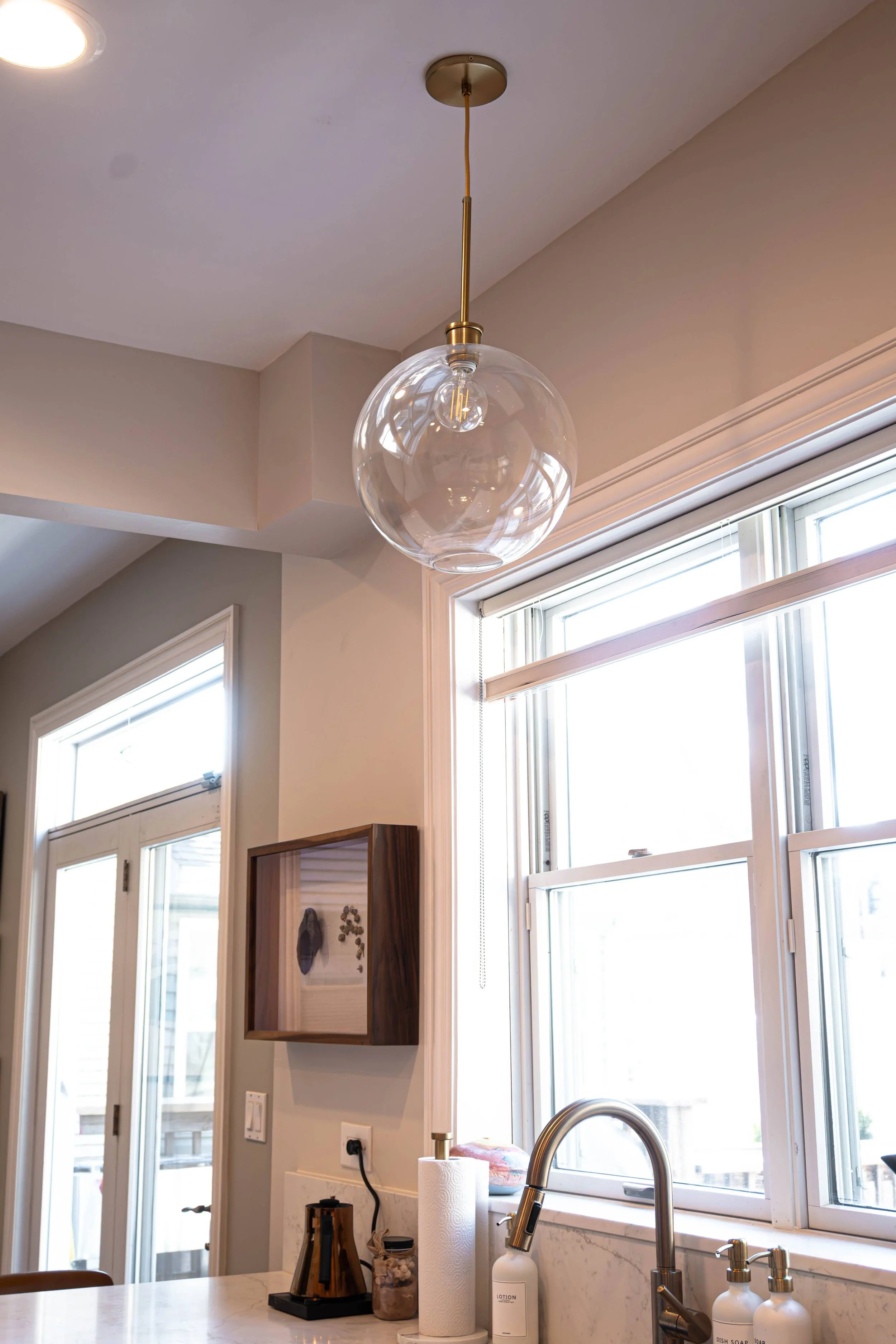 Statement glass bowl pendant lighting provides soft ambient illumination over the island, anchoring the room's modern aesthetic.