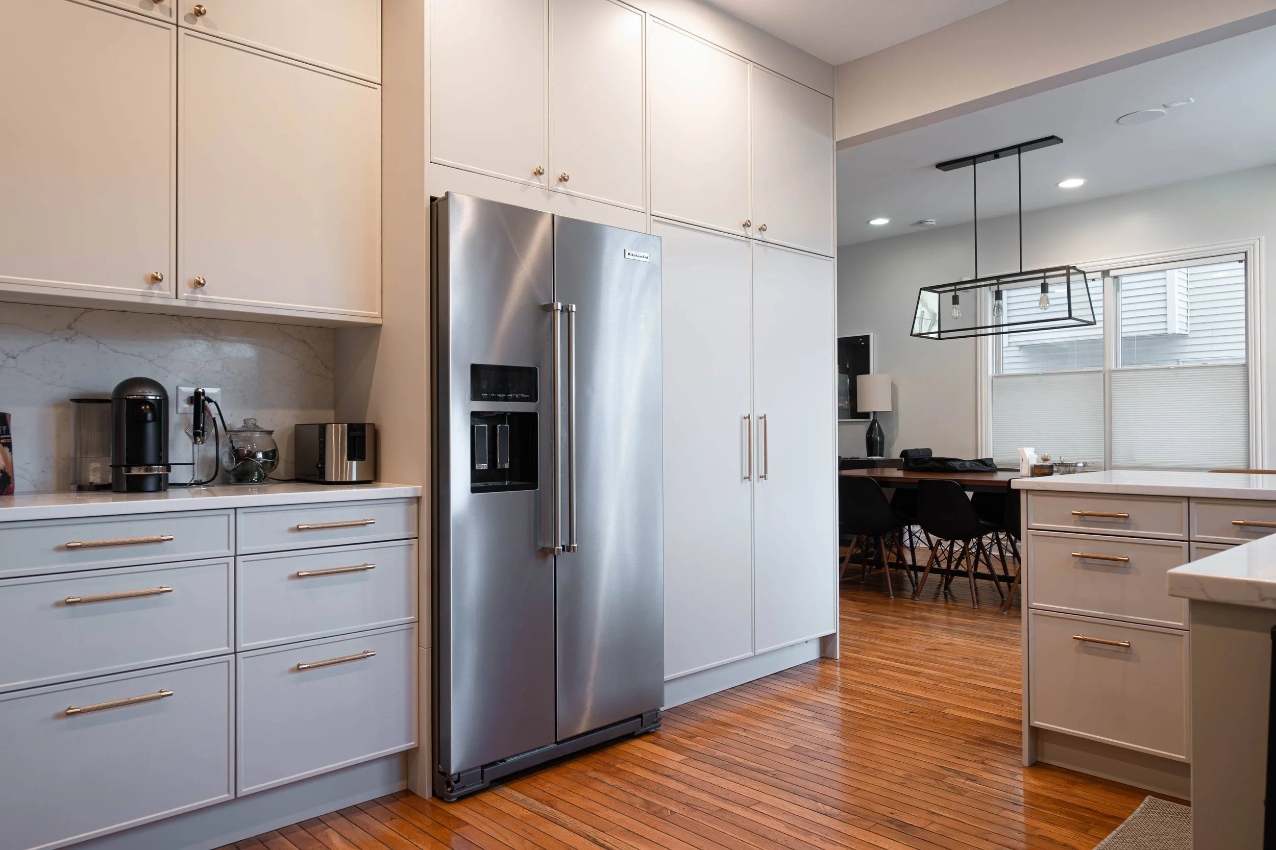Seamless architectural flow from the kitchen to the living area, showcasing refinished hardwood floors and the abundance of natural light in this open floor plan.