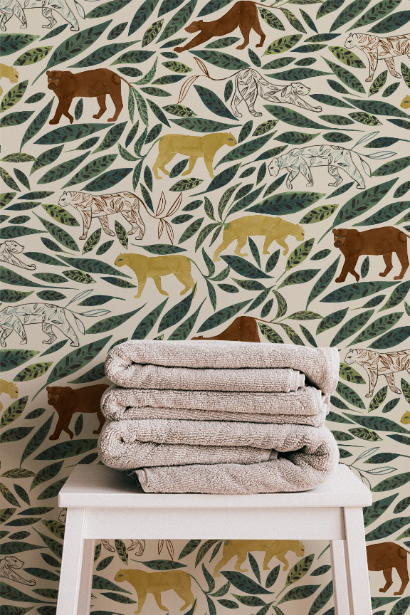 A stack of beige towels on a white table in front of a jungle-themed wallpaper with illustrations of various colored bears and green leaves.