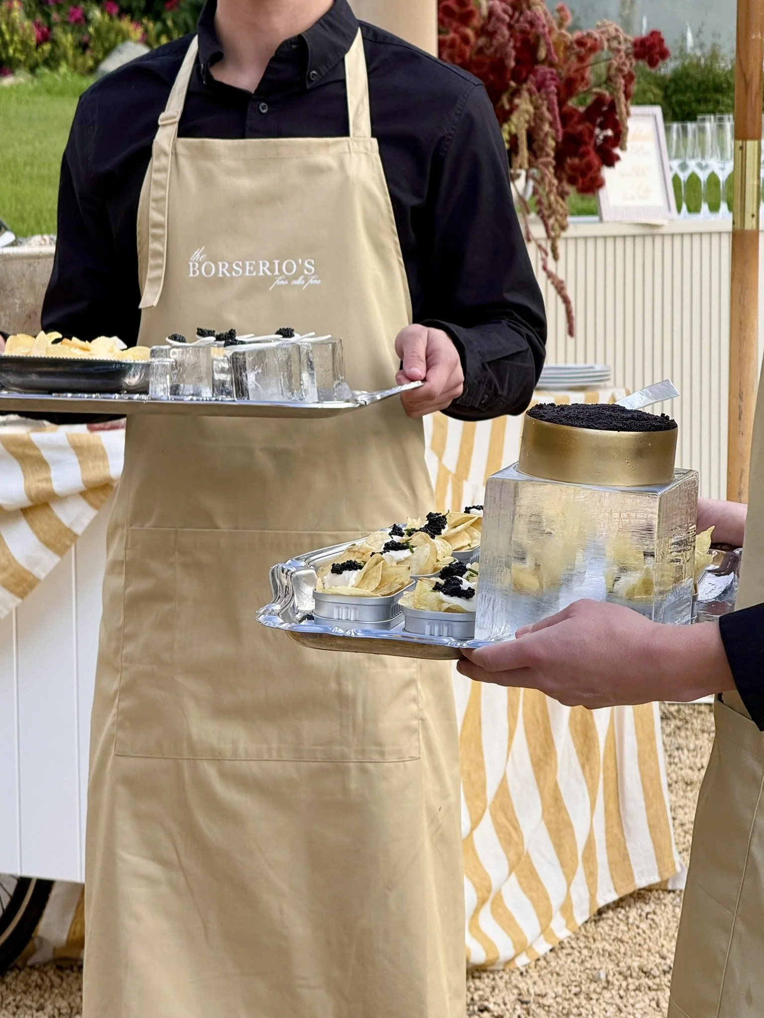 Person wearing a beige apron serving caviar bumps and caviar on chips at a wedding cocktail hour. Shuck Yeach Oyster Catering. 