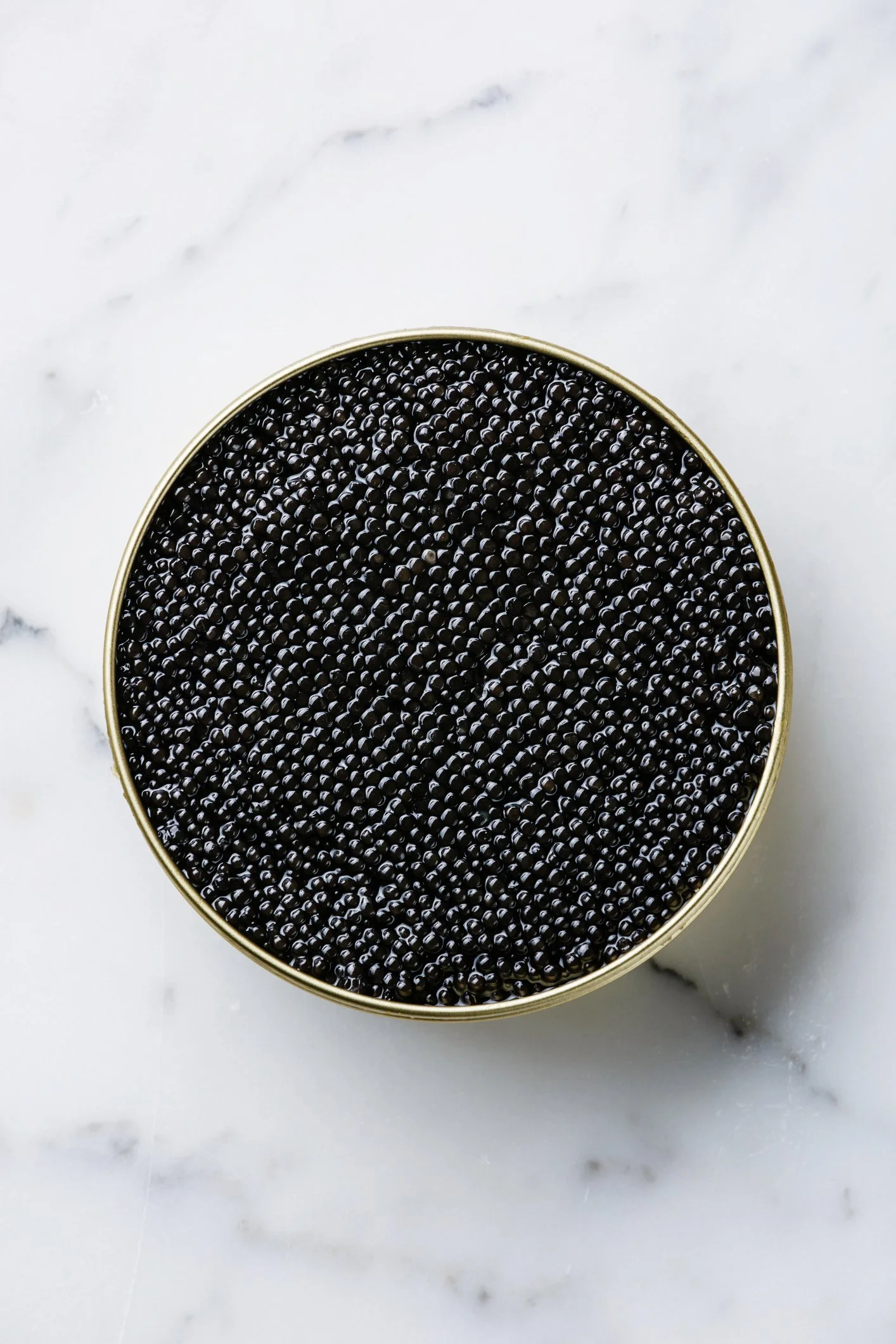 Black caviar in a tin on marble background