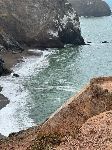 Rocky coastline with ocean waves and steep cliffs.