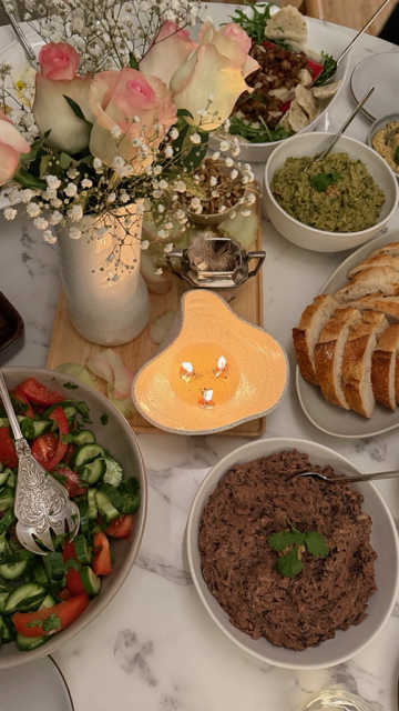 Table set with colorful dishes, bread, dips, and fresh flowers.