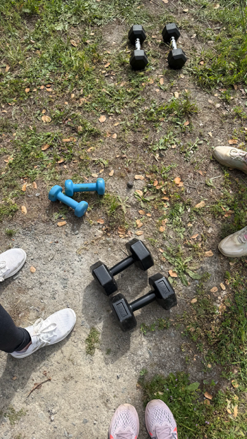 Sneakers and dumbbells outdoors for a group fitness gathering.