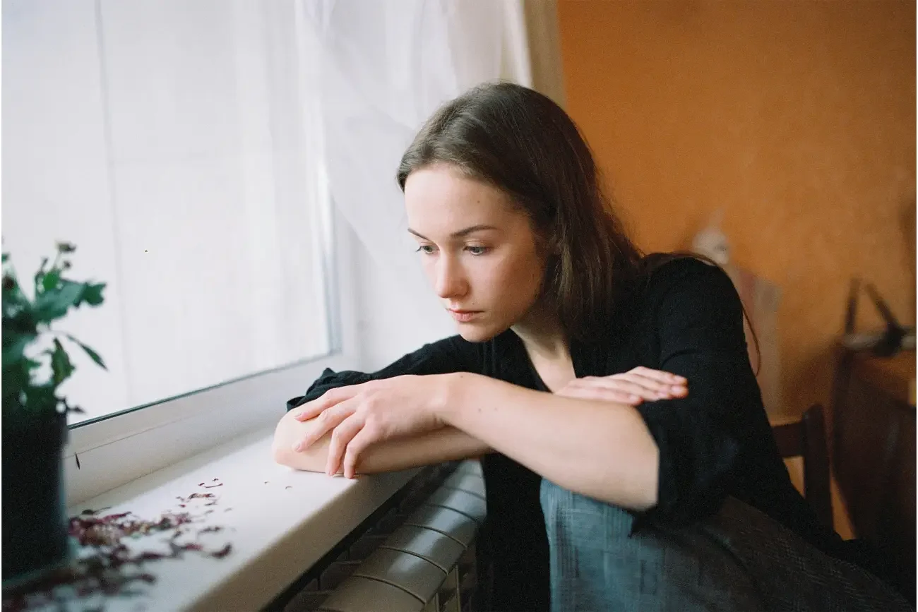 Woman sitting at a window looking worried