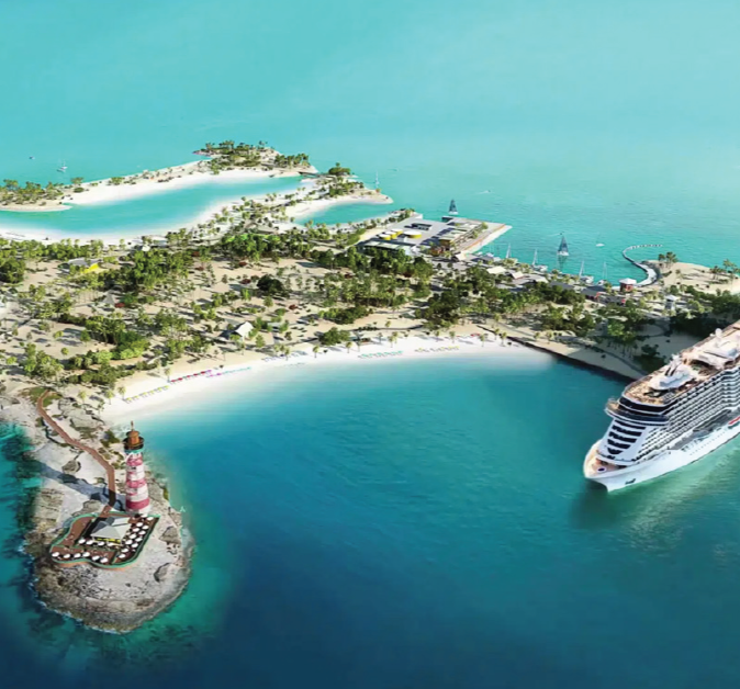 Aerial view of a tropical cruise port with a large cruise ship docked, a lighthouse on a small island, and a sandy beach with lush greenery.