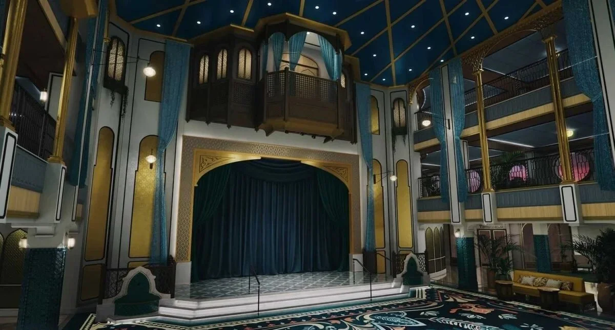 Elegant theater stage with blue curtains, ornate gold and black details, and multiple balconies with seating.