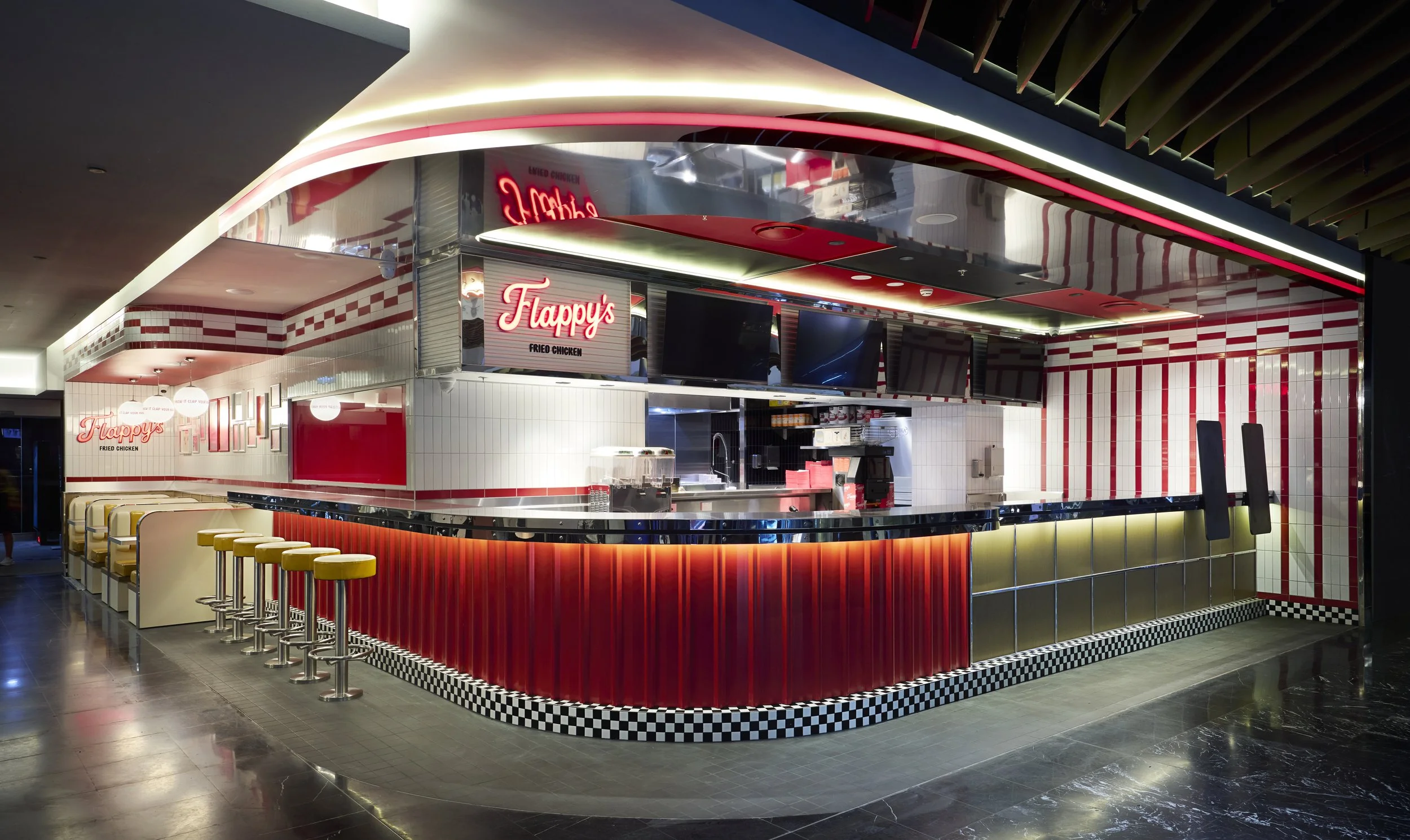A modern fast food restaurant counter named Flappy's with red, white, and yellow decor, checkered pattern along the base, yellow stools in front, and multiple screens above the counter.