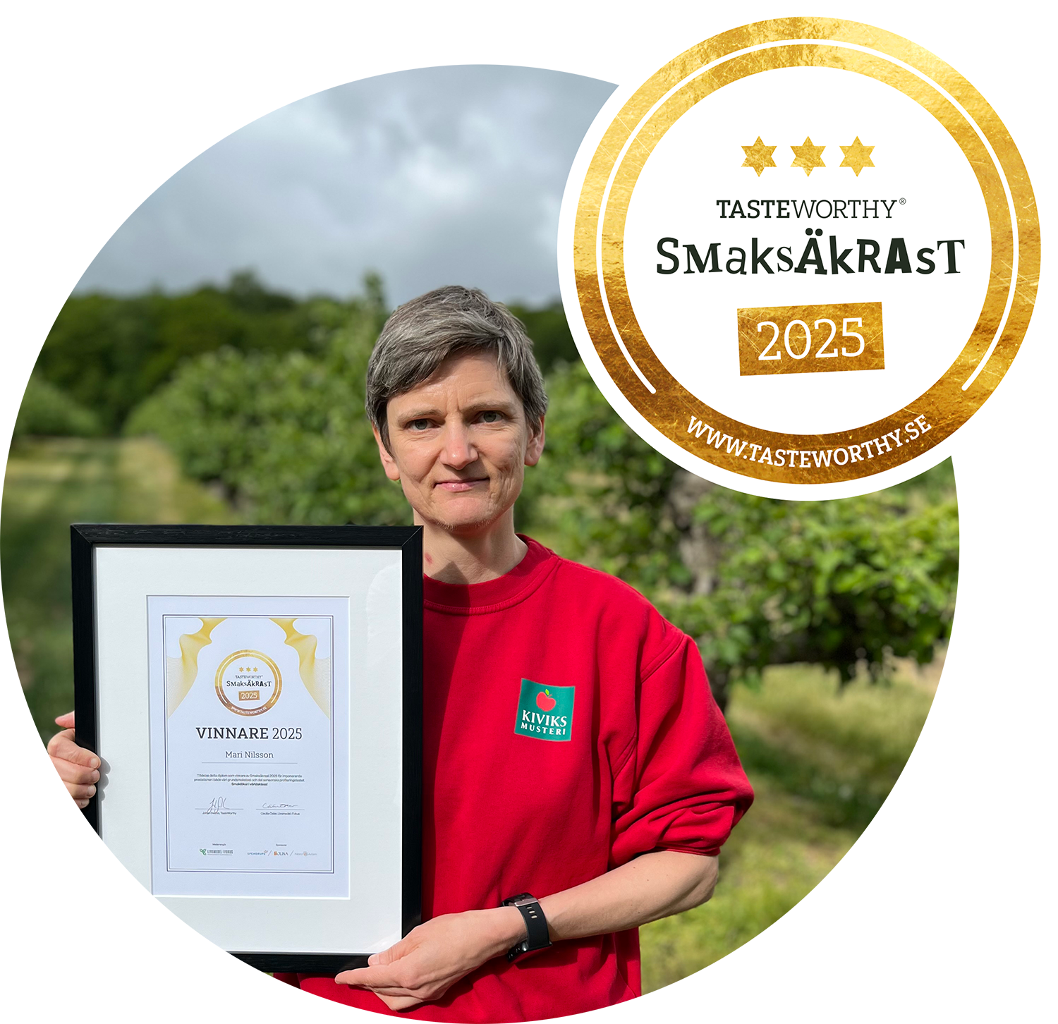 Kvinna som håller ett prisbrev tillsammans med ett certifikat för Tasteworthy SmakÅkRaST 2025 utomhus, bakgrund av gröna träd och en blå himmel.