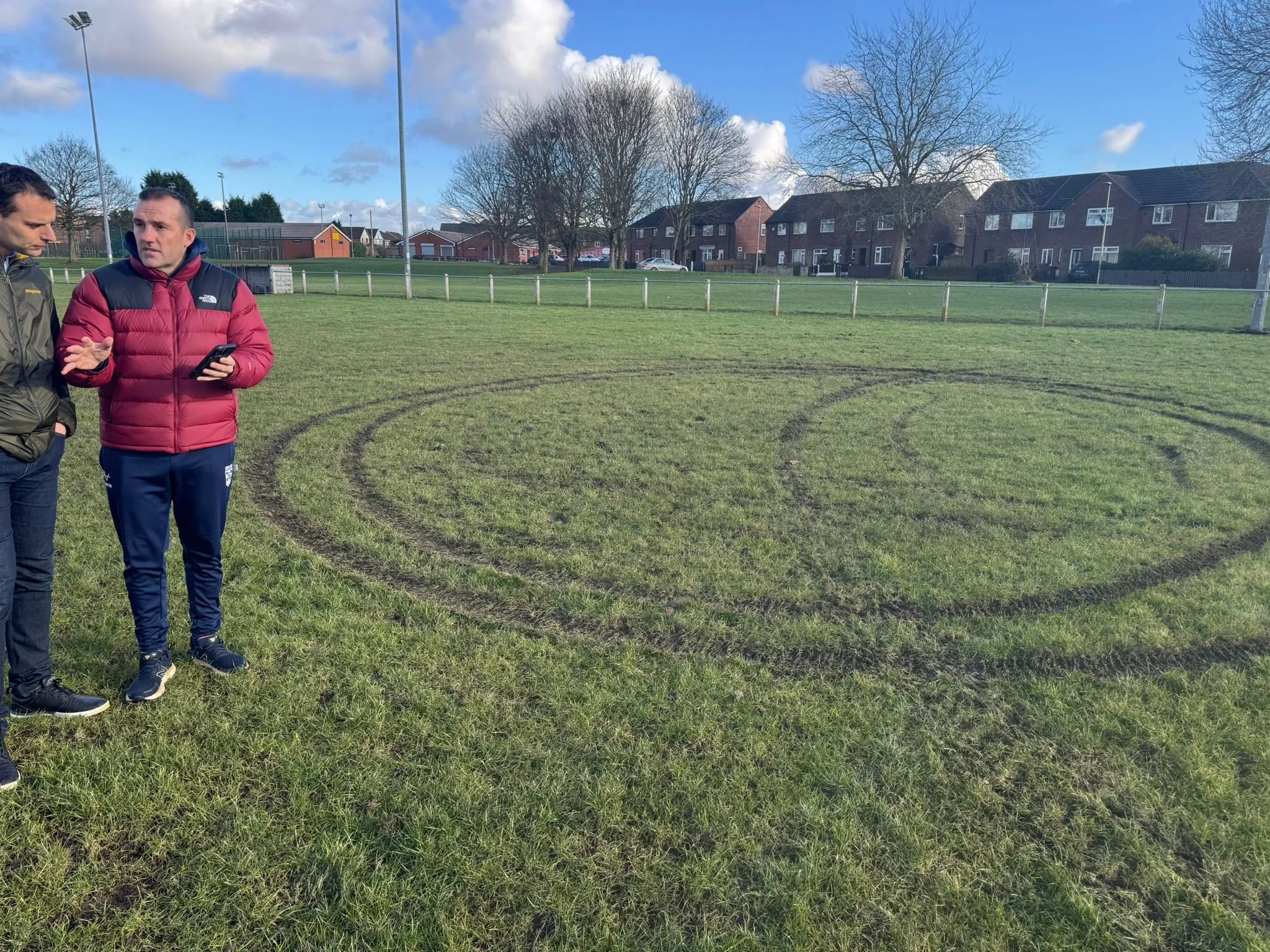 Josh and the coach looking at tyre marks which have damaged the grass pitch