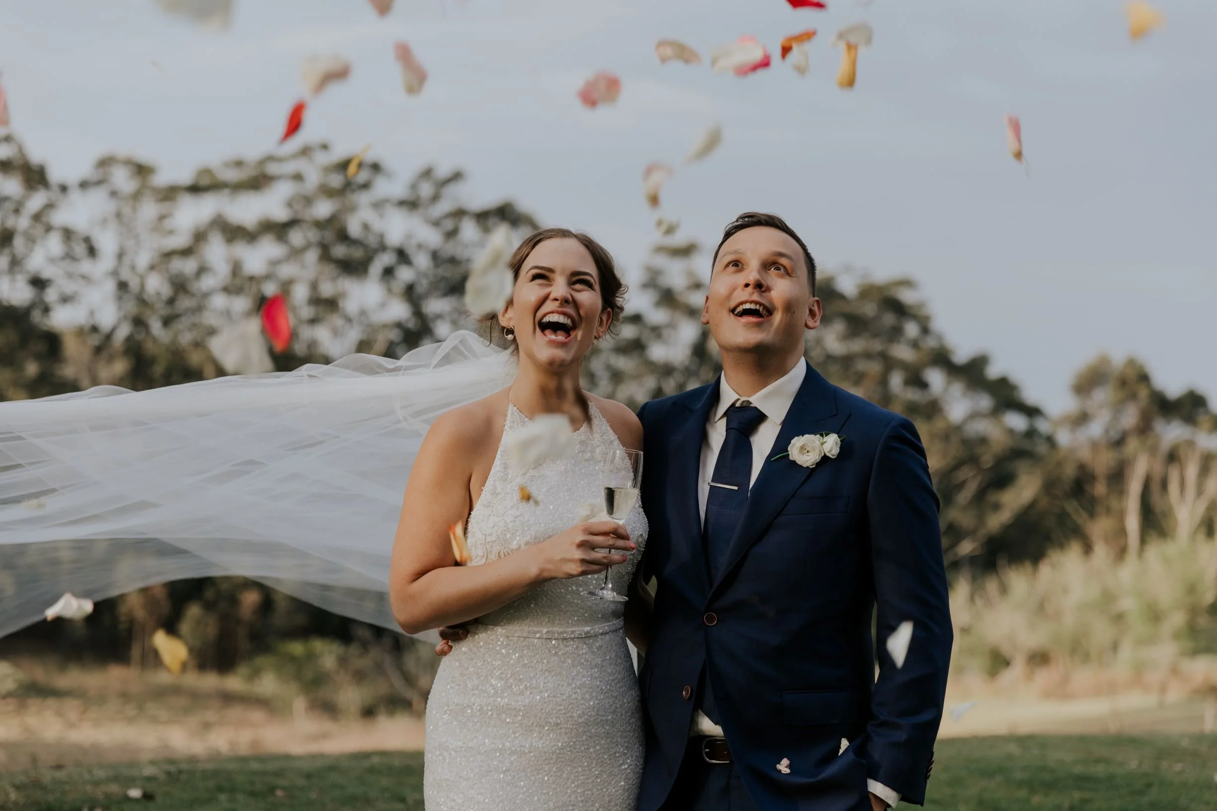A newly married couple laughing beneath falling confetti