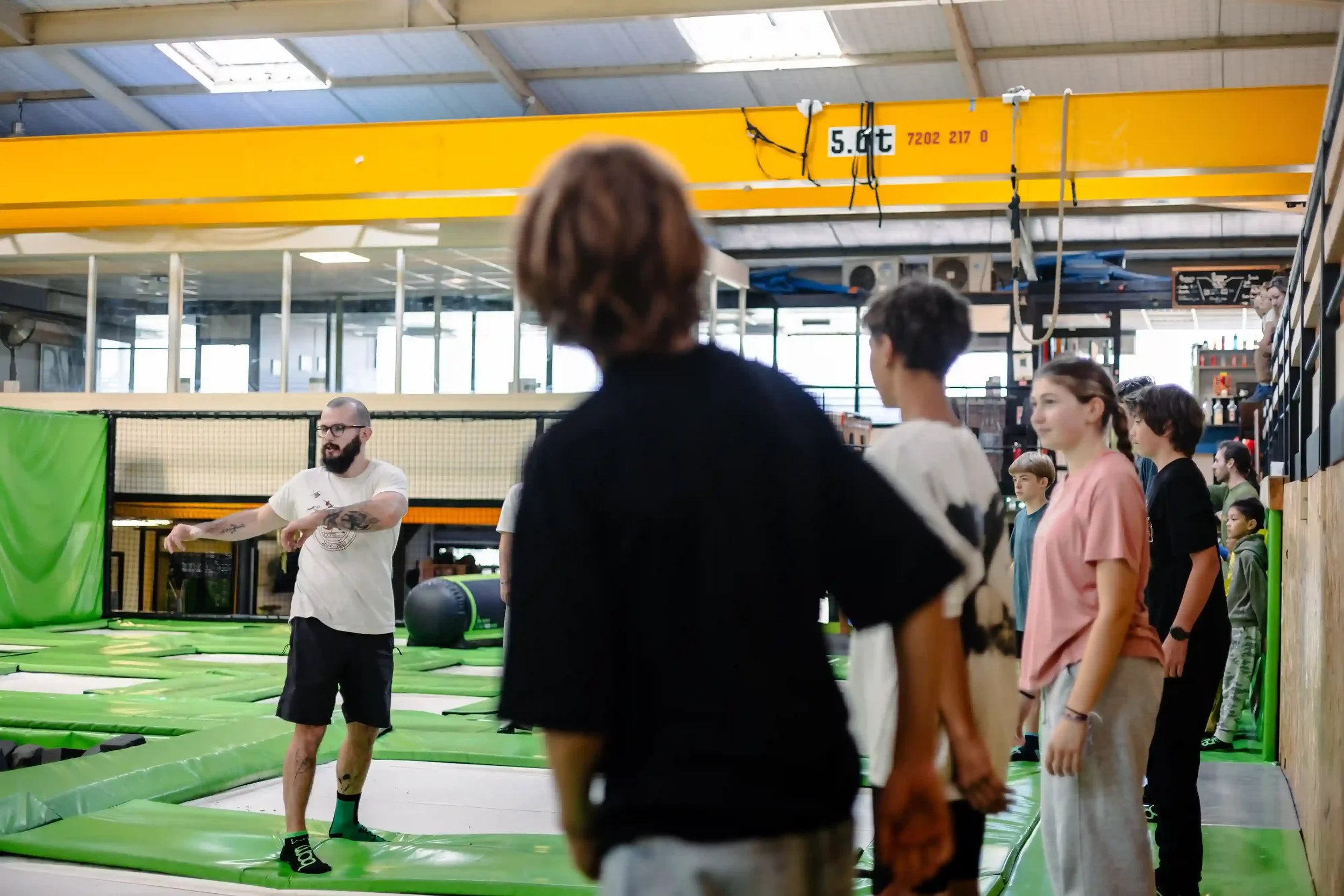 Cours de trampoline freestyle à BAM FREESPORTS avec un coach qui fait un échauffement.