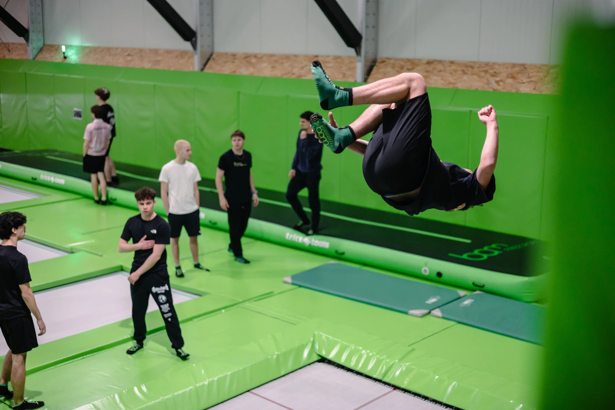 Jeune rider qui fait un salto sous le regard de ses amis dans la salle de BAM FREESPORTS Annecy