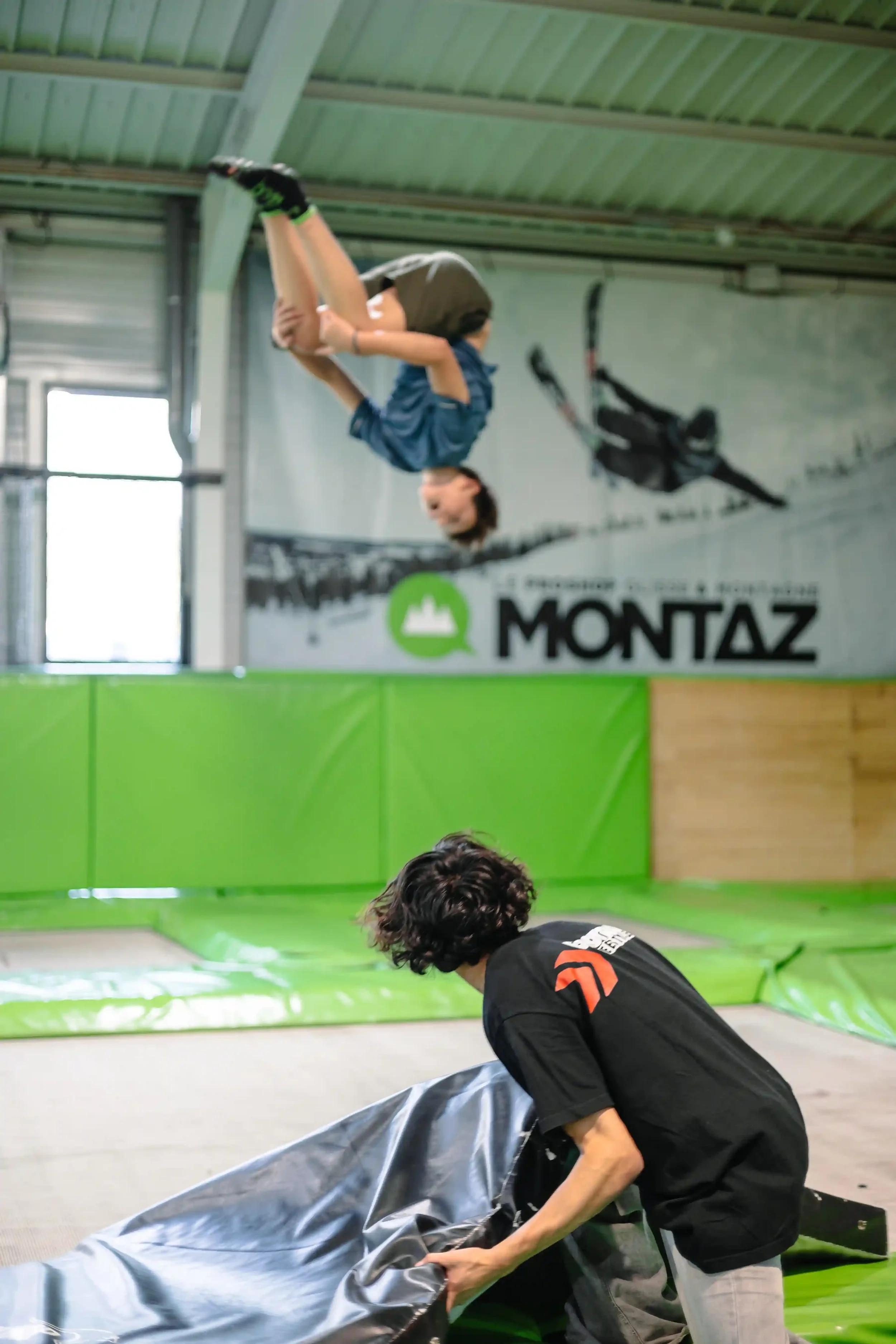 Un coach de BAM FREESPORTS aide un jeune à faire un salto arrière sur un trampoline