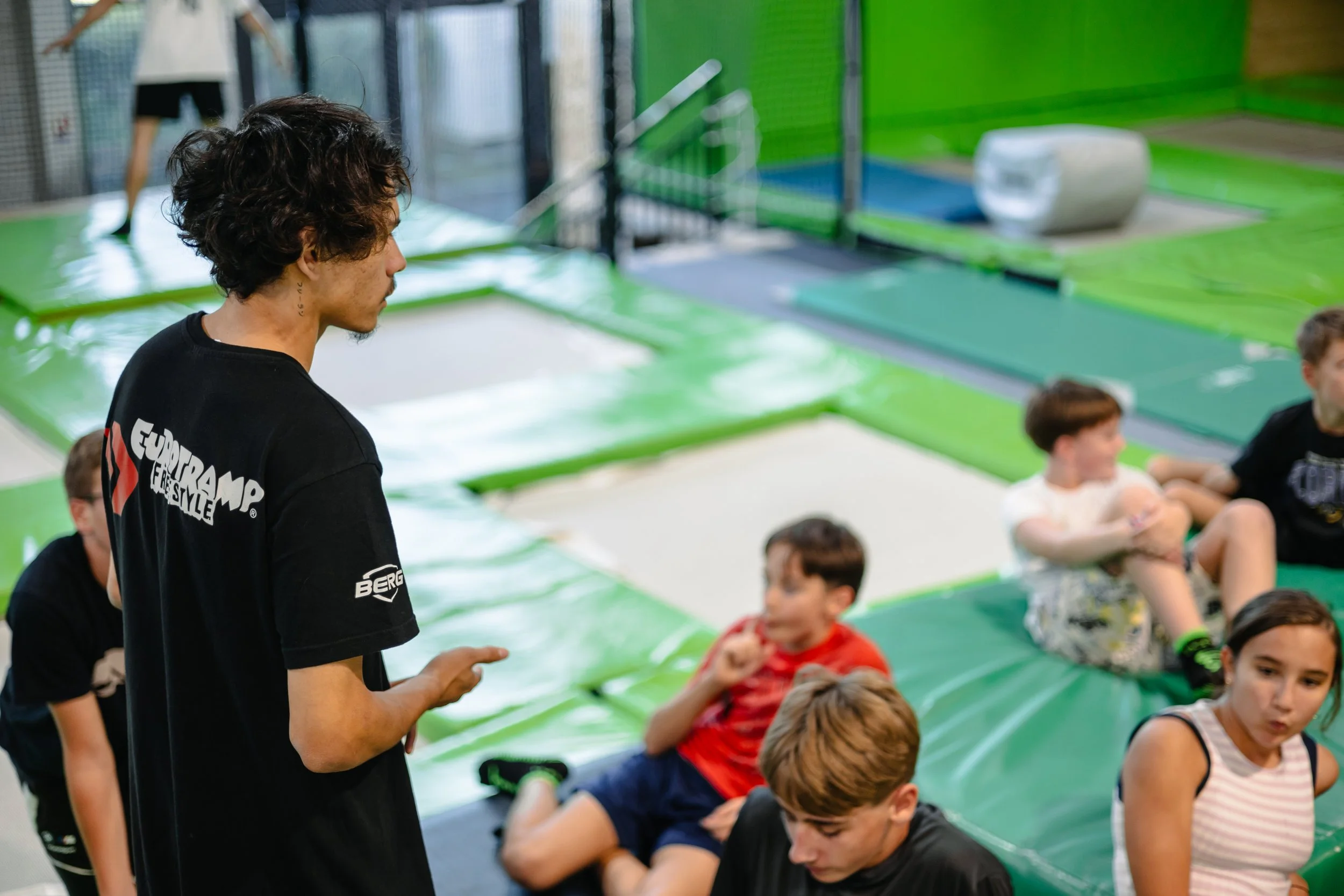 Coach qui donne des instructions au groupe de jeunes avant d'aller sauter sur les trampolines