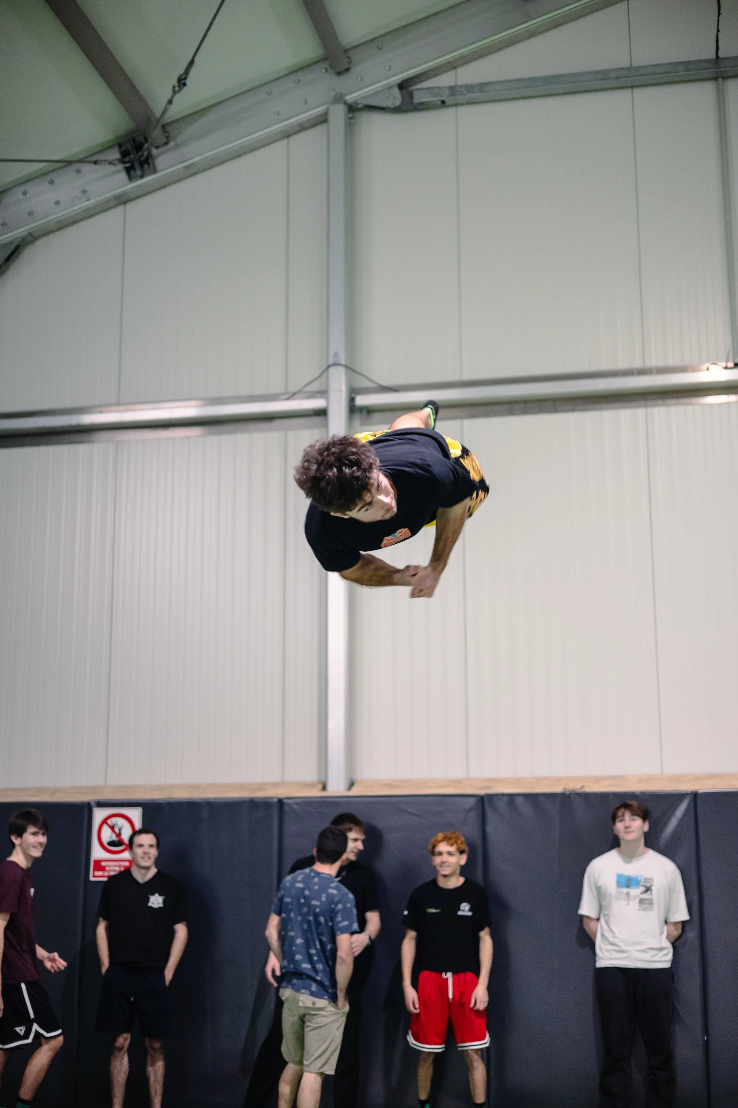 Groupe d'amis qui regarde un jeune homme faire une double vrille sur le méga trampoline de BMA FREESPORTS Annecy