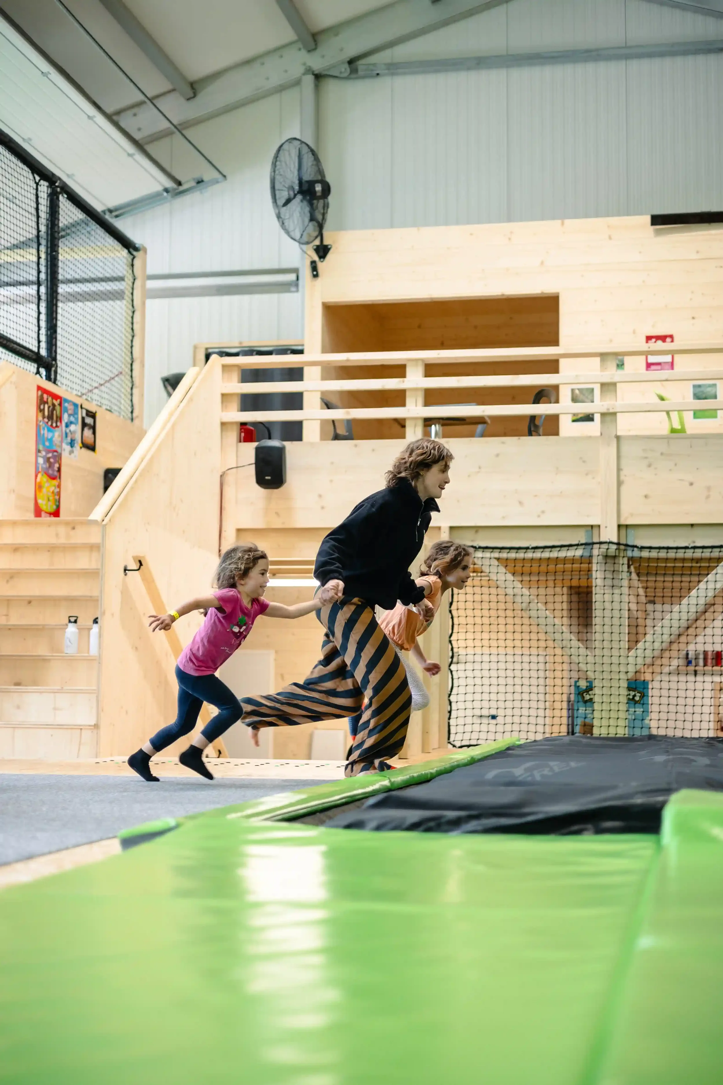 Enfants qui s'amusent avec un membre du staff dans la salle de trampoline de BAM FREESPORTS Annecy