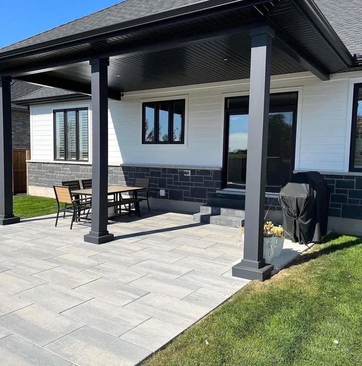 Backyard patio with a covered porch, outdoor dining table, and grilling area. With black columns newly re-done.