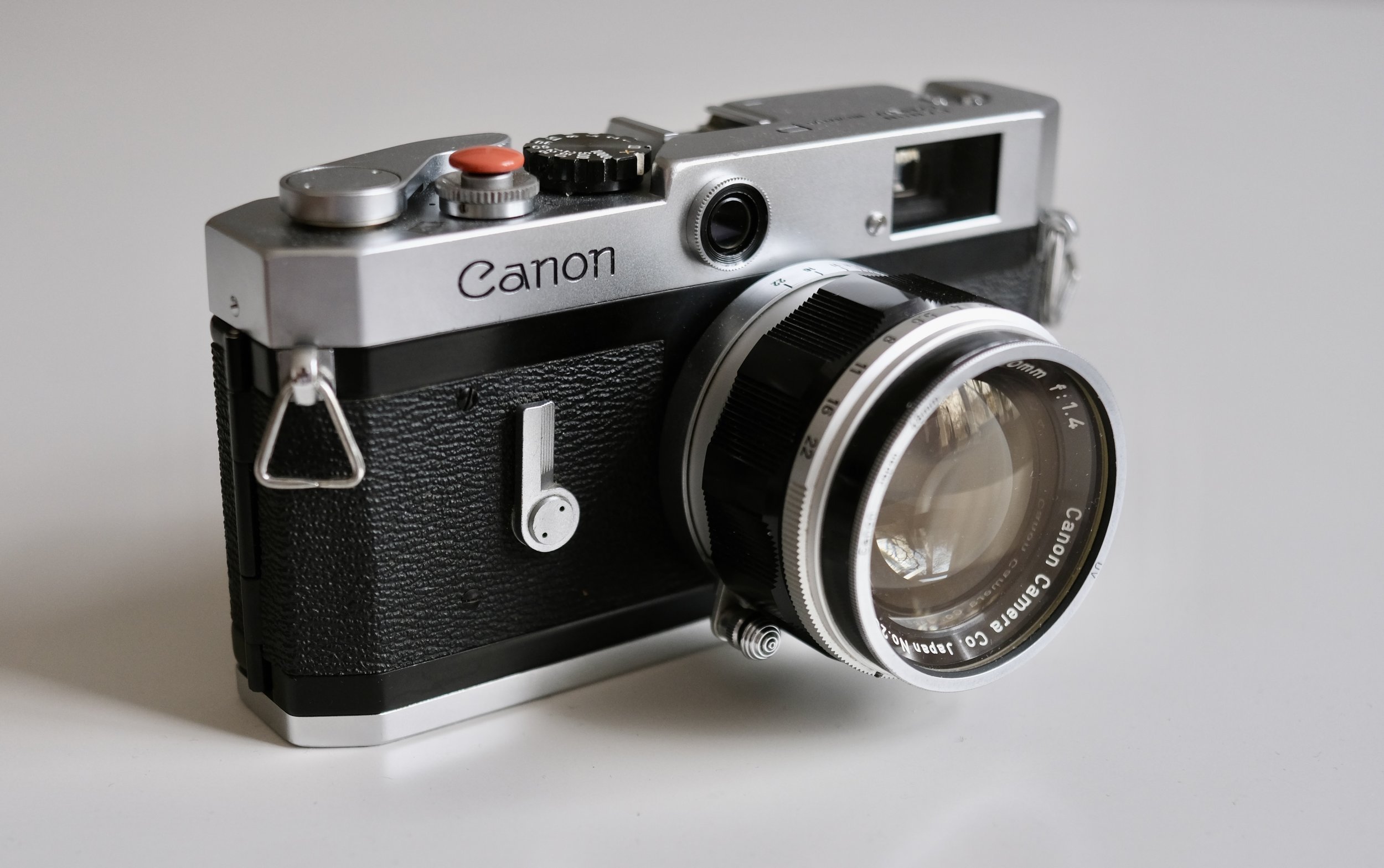 vintage silver Canon P rangefinder camera with a 50mm 1.4 lens on a wooden table.