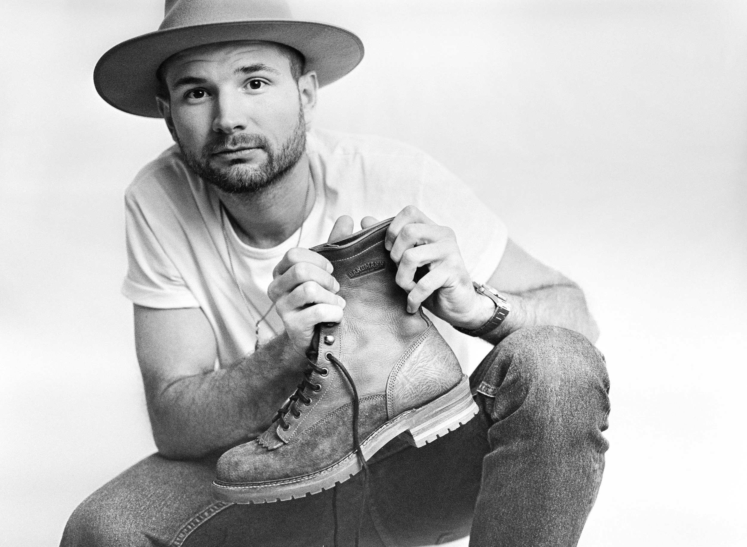 Model in weißem T-shirt hält einen Boot von dem Schuhhersteller Sandmancraft. Analog Ilfold HP5 Film geschossen mit Mamiya 645.