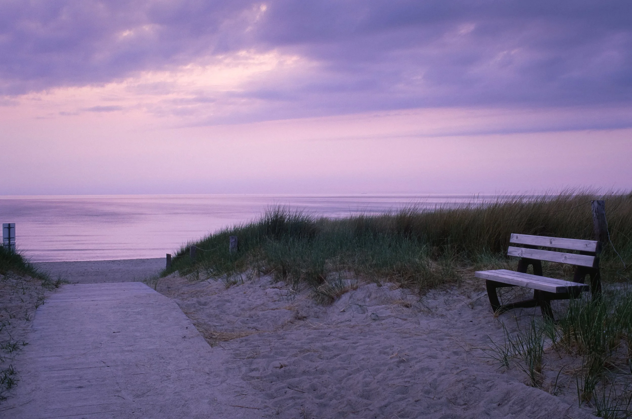 Sonnenuntergang am Strand mit Sand, Dünen und einer leeren Bank. Diernhagen strand auf Fuji Velvia.