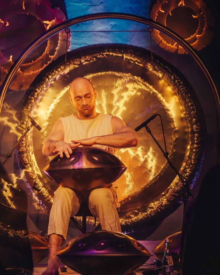 Malte Marten spielt Handpan vor einem leuchtenden Gong in Vilnius
