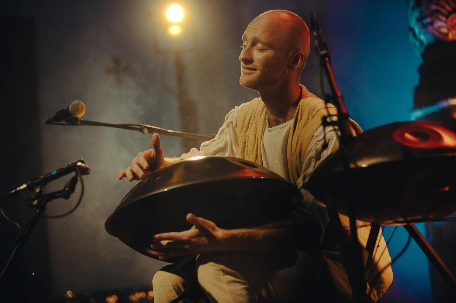Malte Marten spielt Handpan auf der Bühne in warmem Licht