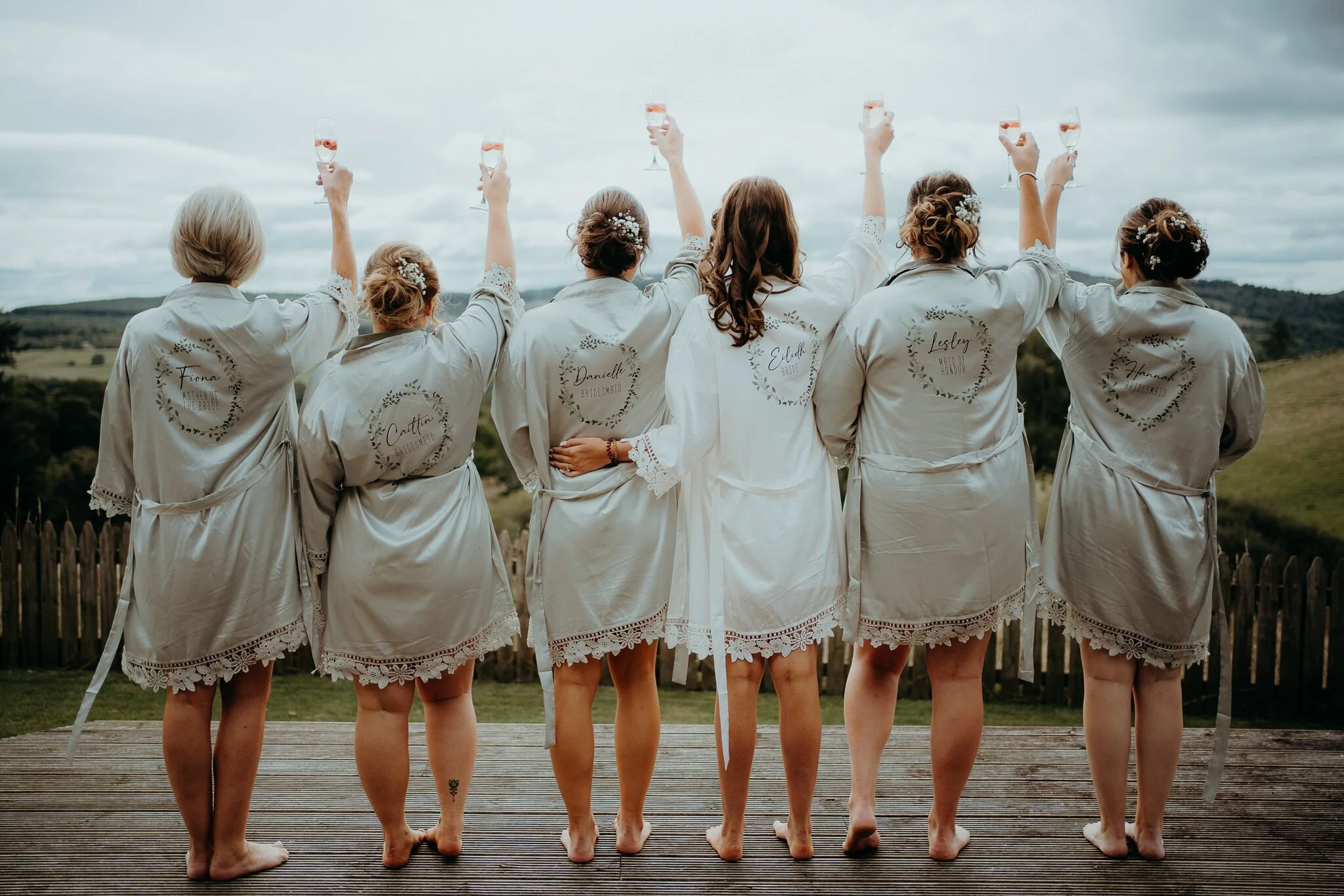 A group of bridesmaids standing on top of a wooden deck