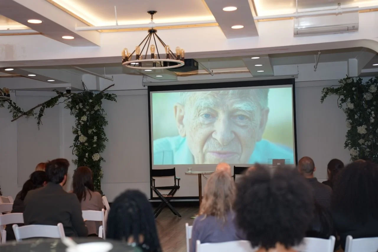 Large screen showing a film of Dr. Arne Fjortoft to seated guests